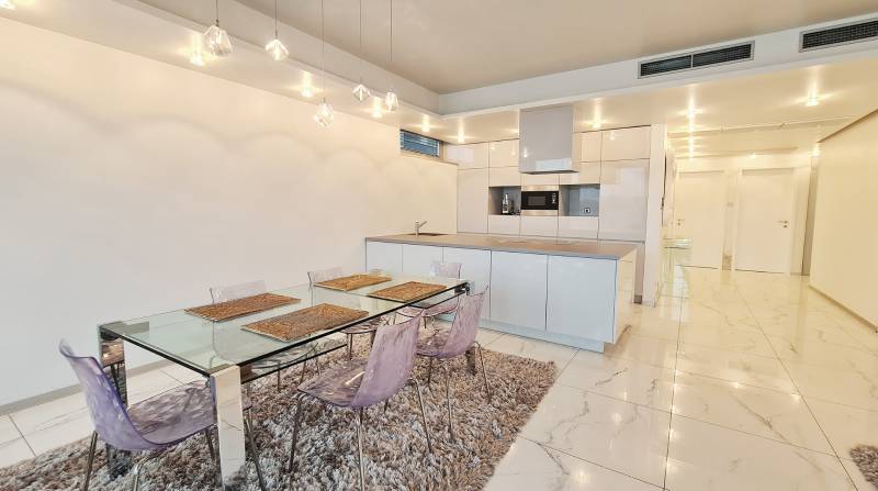 A kitchen in a 3-room apartment with a dining table and white tiles.