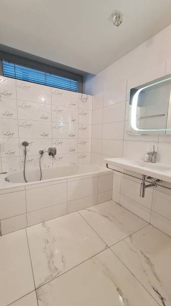 Bathroom with a bathtub and tiles in a 3-room apartment, white and gray color tones.