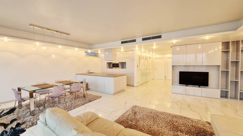 Living room with a kitchen island, dining table, and TV in a 3-room apartment.