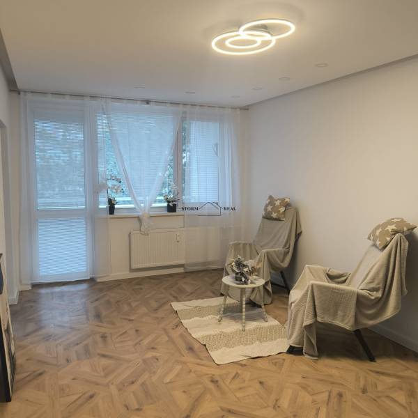 Living room in a 4-room apartment with a wooden decor floor and two armchairs.