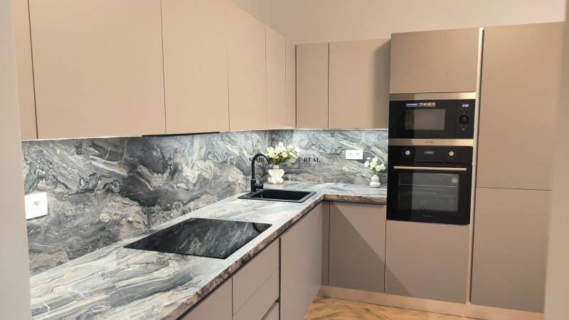 A kitchen with a dark countertop, built-in appliances, and decorative flowers in a 4-room apartment.