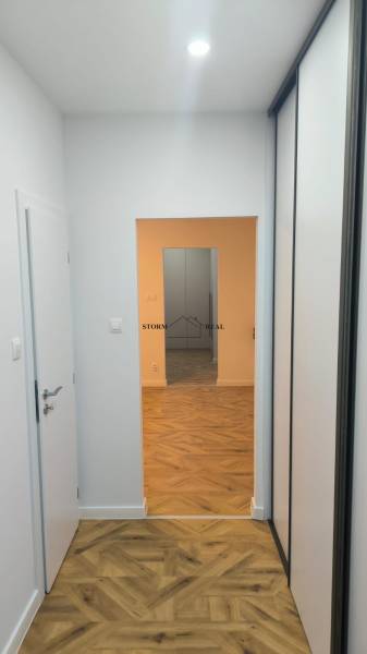 A narrow hallway with a built-in wardrobe and a wooden decor floor in a 4-room apartment.