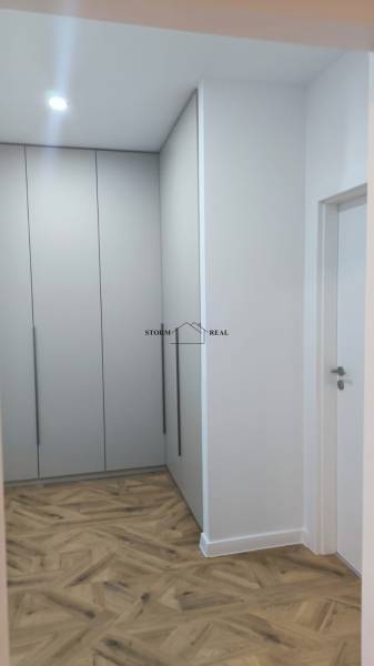 A hallway with white built-in wardrobes and a floor with a wooden decor in a 4-room apartment.