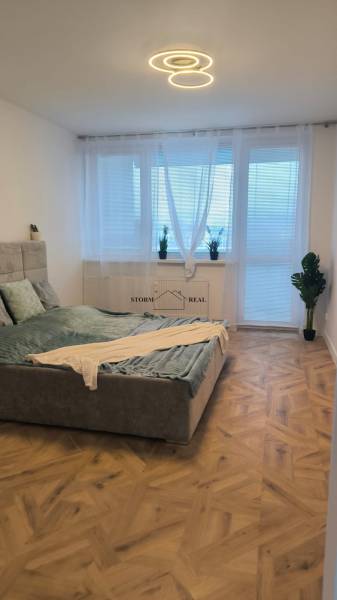 A bright bedroom in a 4-room apartment with a fabric-upholstered bed and a wooden decor floor.