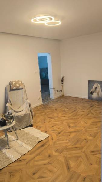 Living room with a chair and wood-patterned flooring in a 4-room apartment.