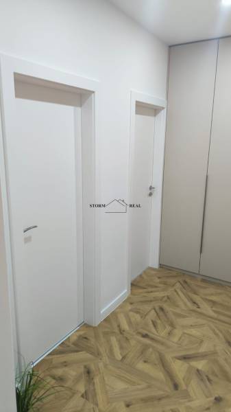 Interior of a 4-room apartment with white doors, cabinets, and a floor with a wood decor.