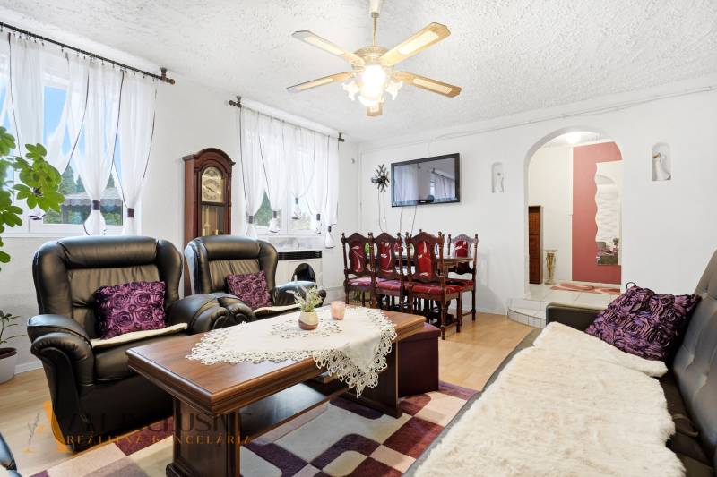 Living room of a family house with a fireplace, black sofas, and a floor with a wooden decor.