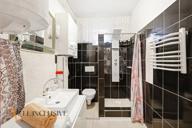 Bathroom with a shower, sink, and mirror in a family house.