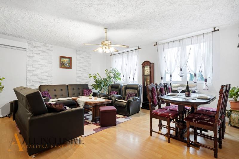 Living room in a family house with a wood-patterned floor, a sofa, and a dining table.