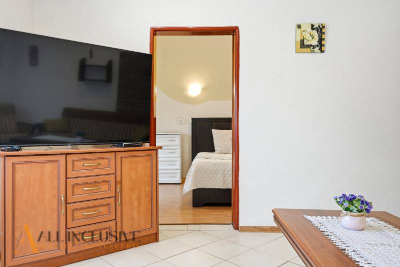 Interior of a family house with a large television, open doors to the bedroom, decorations.