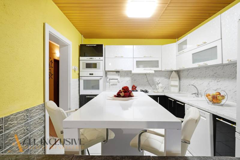 A kitchen with a white countertop, yellow walls, and modern appliances in a family house.