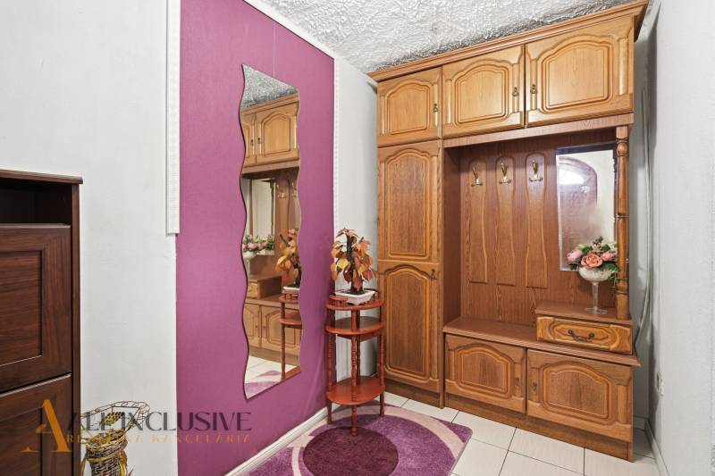 Interior of a family house with a coat closet, mirror, and decorations on a purple wall.