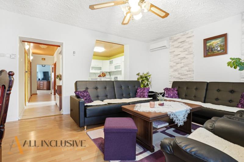 Living room in a family house with a wooden decor floor and black leather sofas.