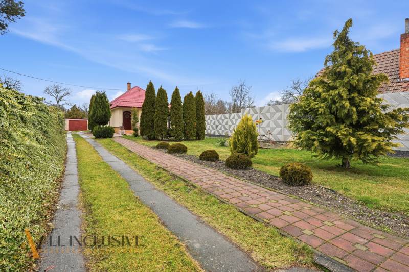Driveway and garden surrounding the family house in Čierny Brod with conifers.