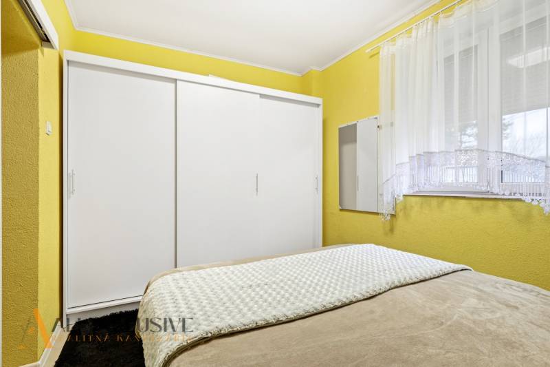 Bedroom in a family house with a simple white wardrobe and yellow walls.