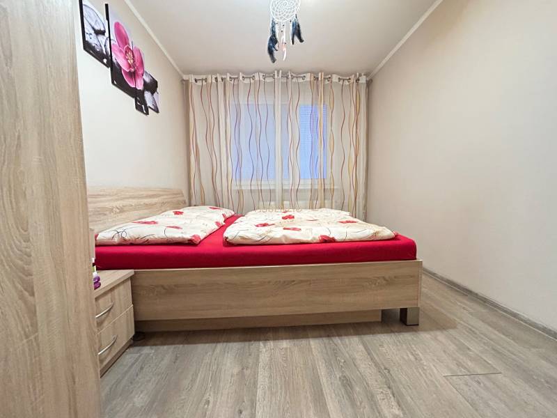 Bedroom in a two-room apartment with a bed and a floor with a wooden decor.