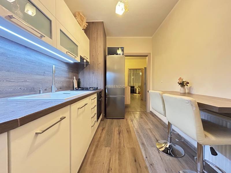 A kitchen in a 2-room apartment with a wooden decor floor and a bar counter.