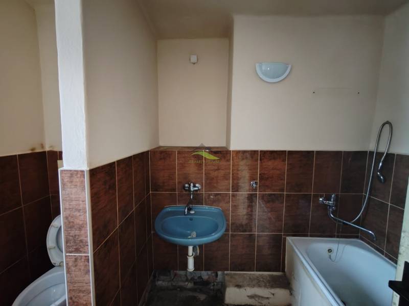 A bathroom in a 2-room apartment with a bathtub, sink, and toilet, tiled.