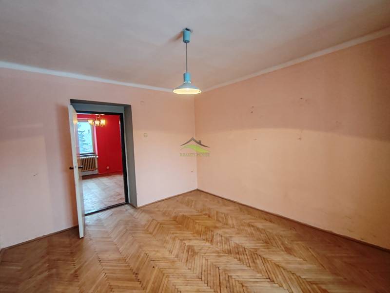 A room in a 2-room apartment with a wooden decor floor and simple lighting.