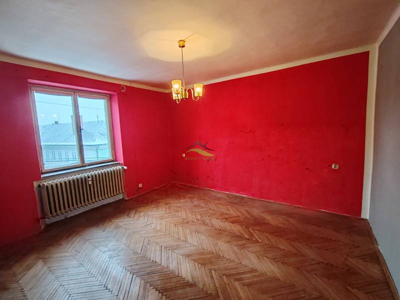 A room with red walls and a wooden decor floor in a 2-room apartment.