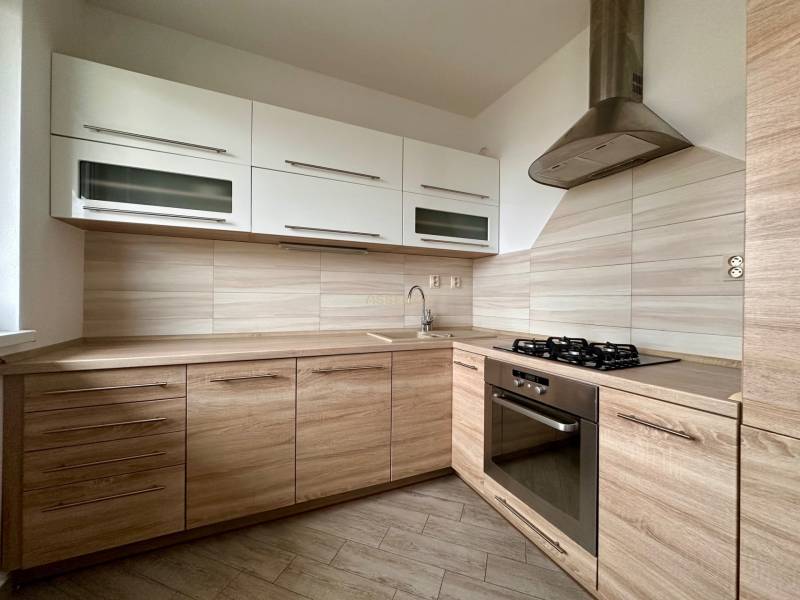 A kitchen in a 3-room apartment with a wooden decor floor and modern appliances.