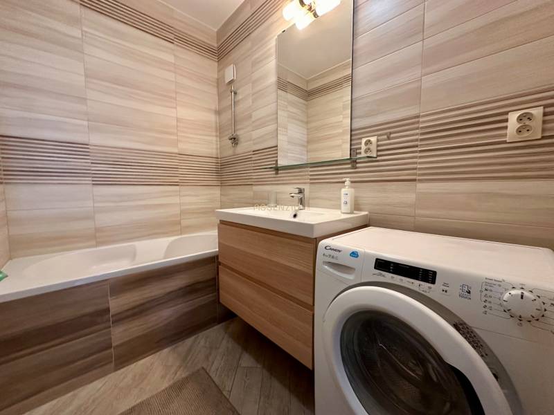 Bathroom with a bathtub, sink, and washing machine in a 3-room apartment.