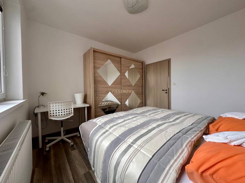 Bedroom in a 3-room apartment with a bed, wardrobe, desk, and floor with a wooden decor.