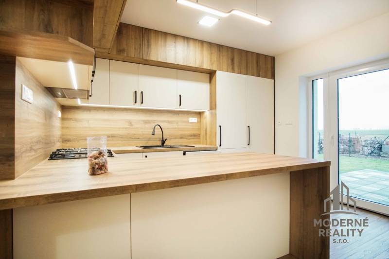 A kitchen with a wooden decor floor, bright atmosphere, and a view of the garden.