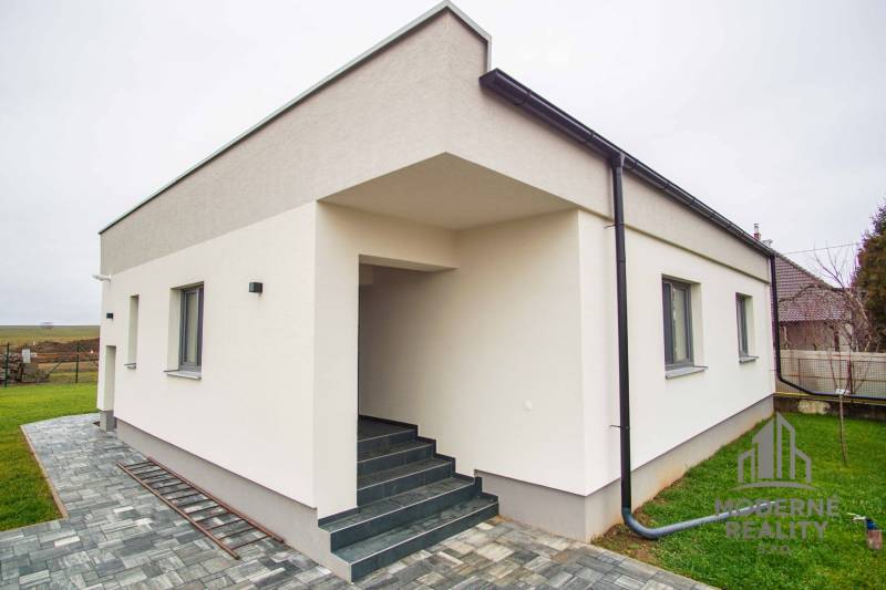 A family house in Branovo with a white facade and a paved walkway at the entrance steps.