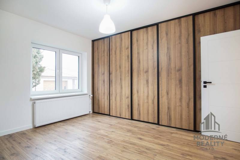 A room with a wooden decor floor and a large built-in wardrobe in a family house.
