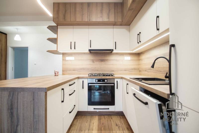 A kitchen in a family house with white cabinets and a wooden decor floor.