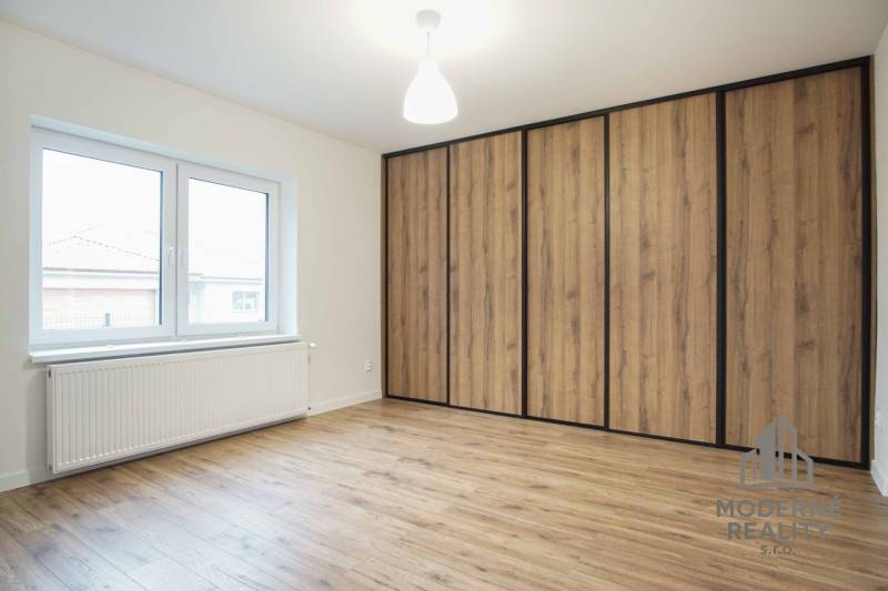 A room in a family house with a wooden decor floor and a large built-in wardrobe.