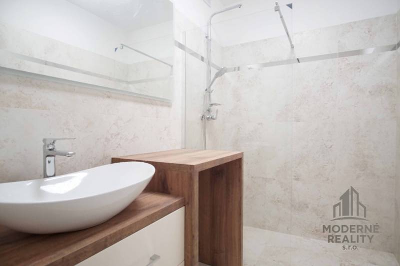 A bathroom in a family house with a sink on a wooden decor and a shower corner.