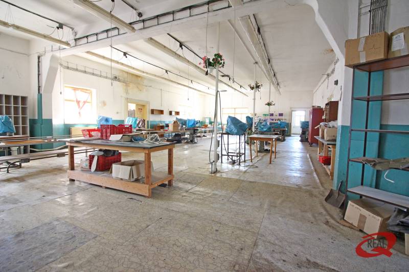 Interior of a building with a large hall, work desks, and shelves.
