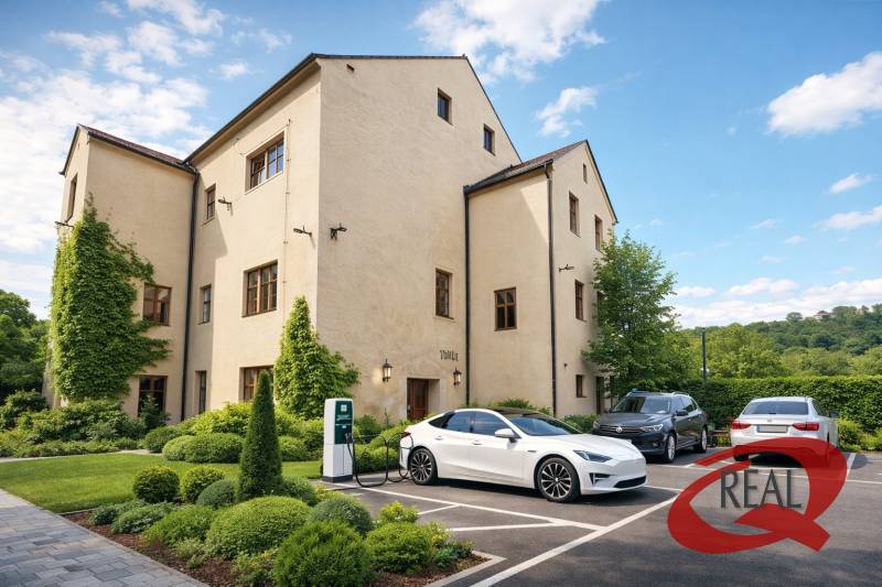 A building in Veľké Uherce with greenery and a charging station for electric cars in the parking lot.