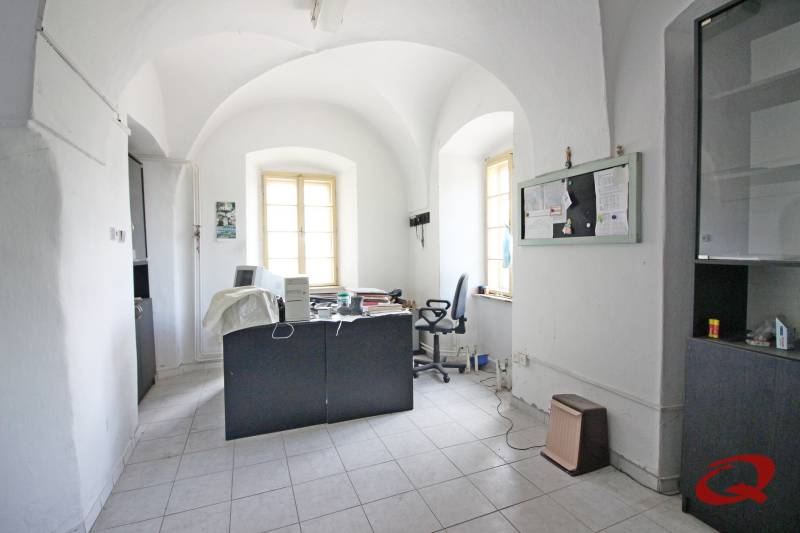 Office in a building with curved ceilings, a desk, and two windows.
