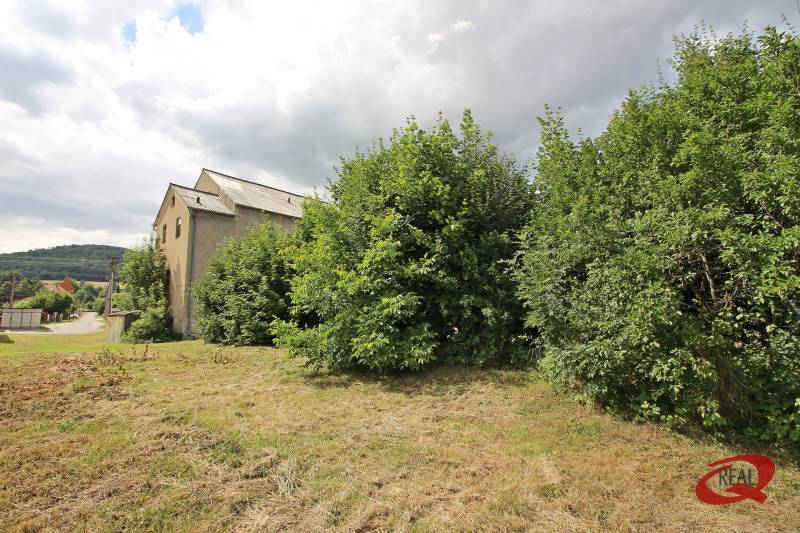 A building in Veľké Uherce surrounded by greenery, with a view of the hilly landscape.