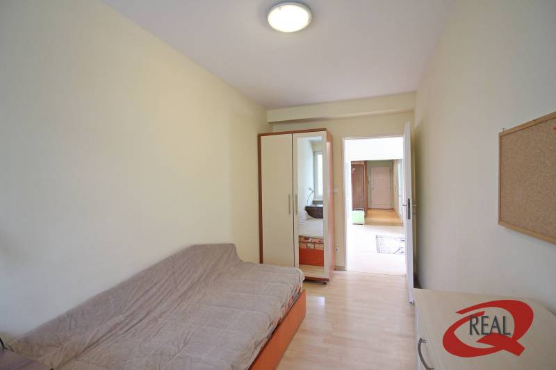 A room in a 3-room apartment with a sofa, built-in wardrobe, and a floor with a wooden decor.