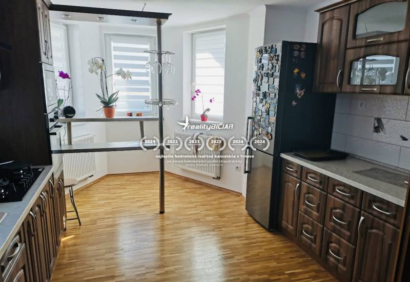 A kitchen in a family house with a wooden decor floor, dark furniture, and a bar counter.