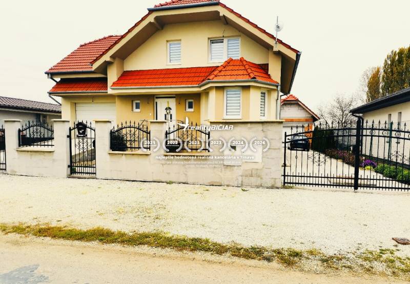 A family house in Ratkovce with a red roof, fenced entrance gate, landscaped garden.