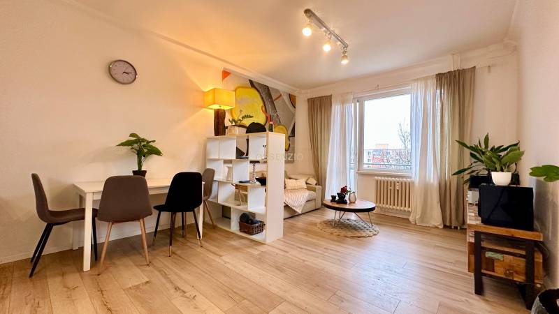 Living room in a two-room apartment with a wooden decor floor and light furniture.