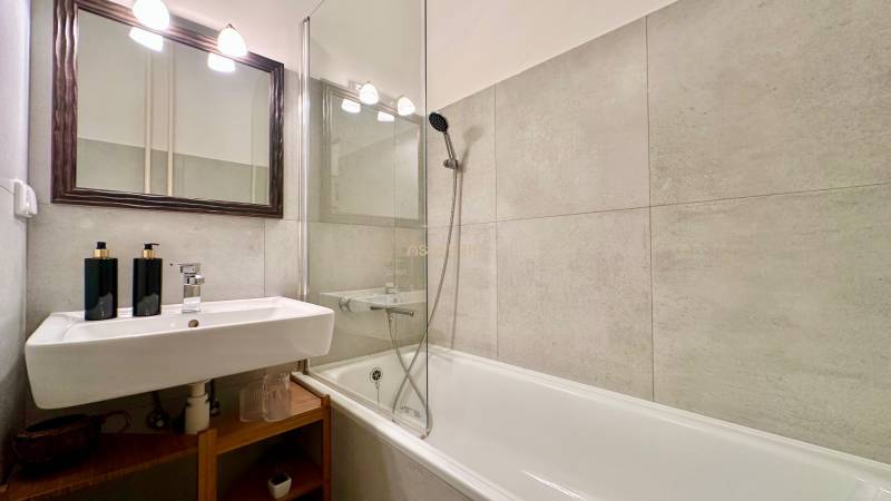 Bathroom with a bathtub and a sink in a 2-room apartment, beige tiles.