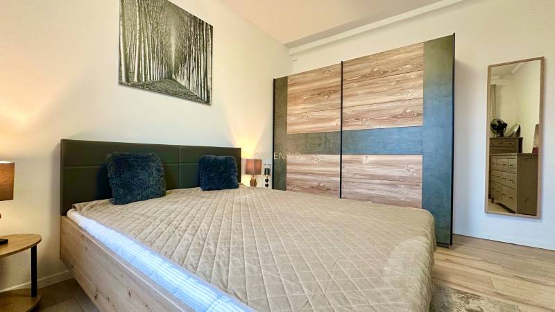 Bedroom in a 2-room apartment with a wood-decor floor and a spacious wardrobe.