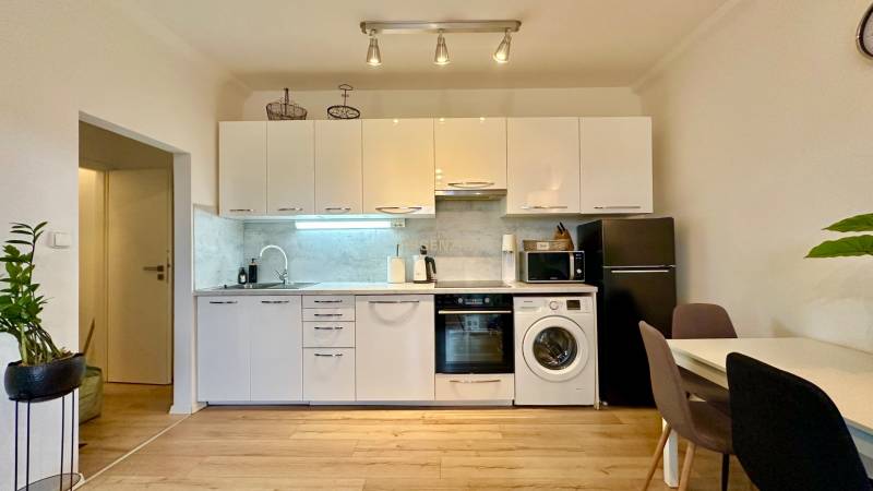 A kitchen in a 2-room apartment with white cabinets and a wood-patterned floor.