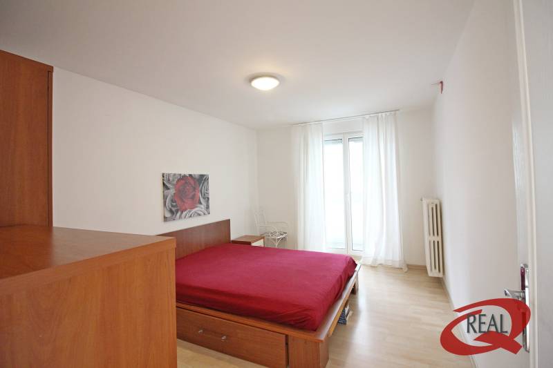 A bedroom in a 3-room apartment with a bed and a wooden decor floor.