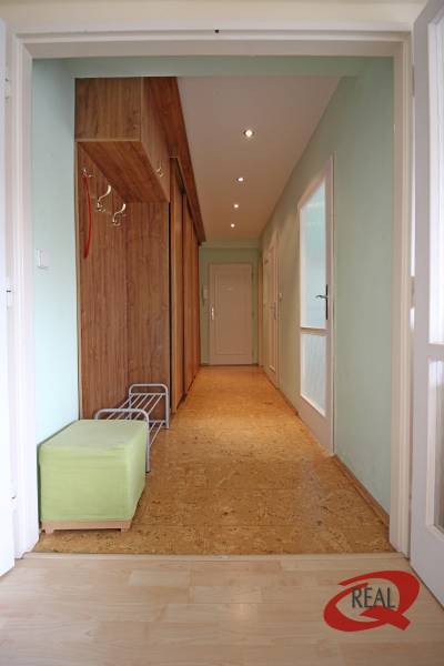 Entrance hallway in a 3-room apartment with wooden decor furniture and green seating.