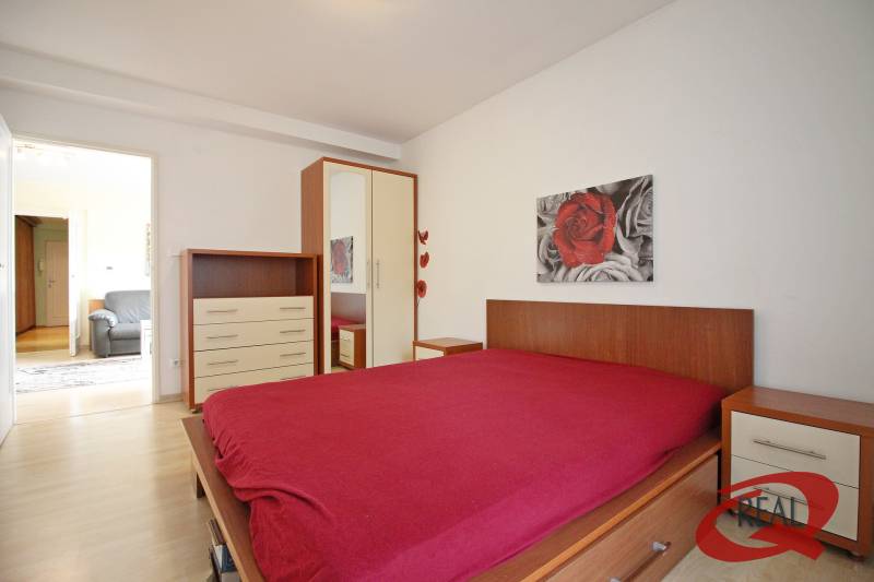 A bedroom with a wood-decor floor, a bed, a cabinet, and a painting in a 3-room apartment.