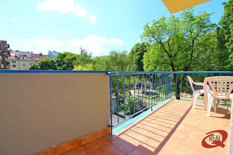 Balcony of a 3-room apartment with a view of greenery and a children's playground.