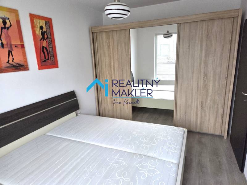 Bedroom with a double bed and a wardrobe in a studio apartment, decorative paintings on the wall.