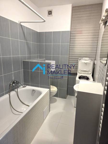 Bathroom with a bathtub, sink, and washing machine in a studio apartment.